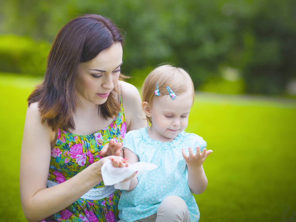 mom use baby wipes to clean baby's dirty hands on park